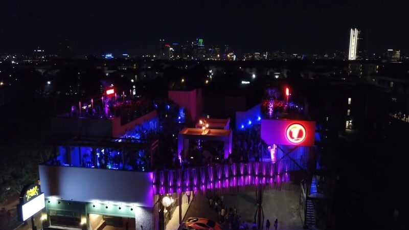 Rooftop bar in Dallas illuminated with vibrant neon lights at night