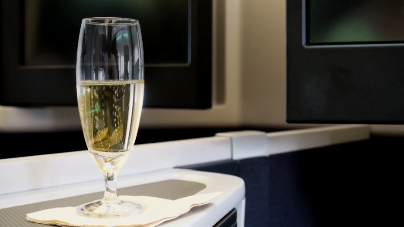 A glass of champagne sits on a first class seat console before takeoff